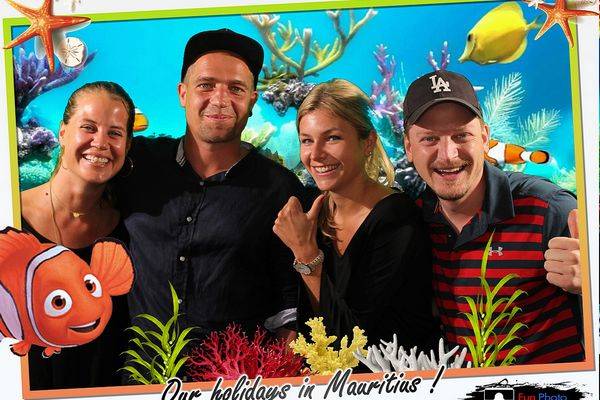 Tourist couples having fun taking a photo in front of photobooth at hotel in Mauritius with under water background